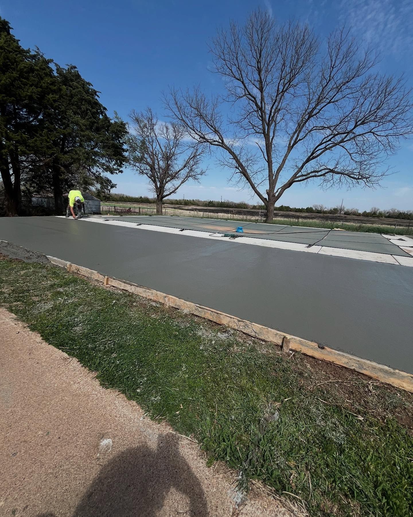 A shadow of a person is cast on a concrete road.