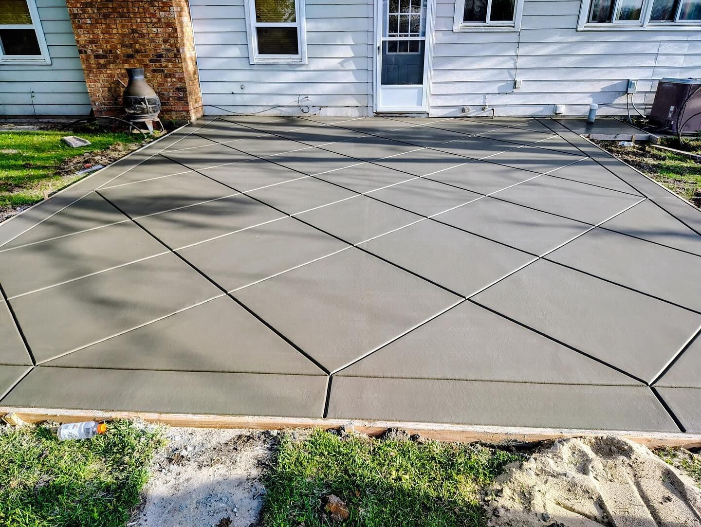 A concrete patio is being built in front of a house.