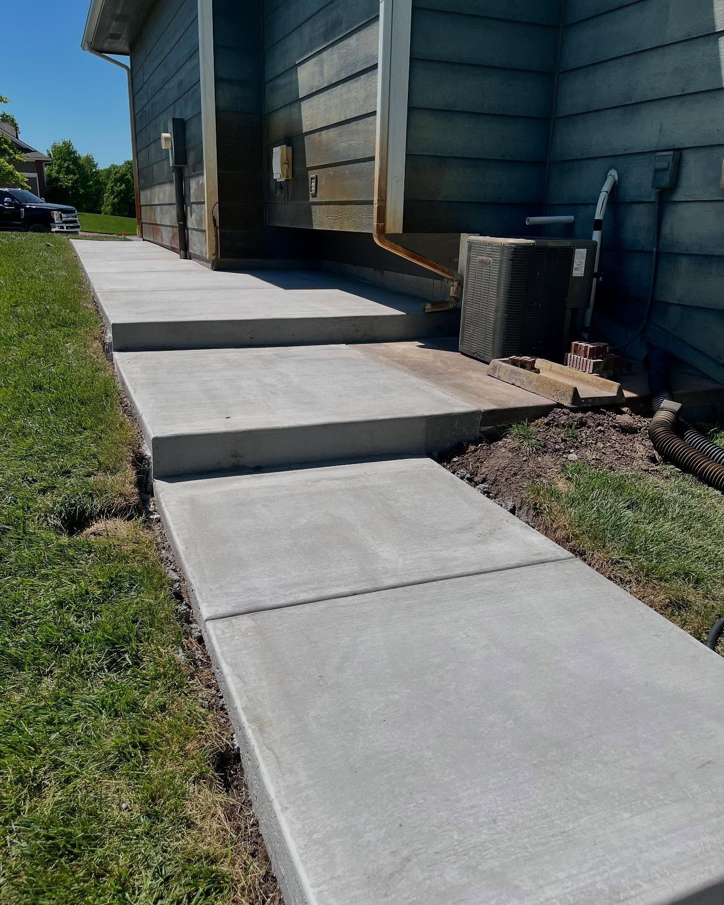 A concrete walkway leading to the side of a house.
