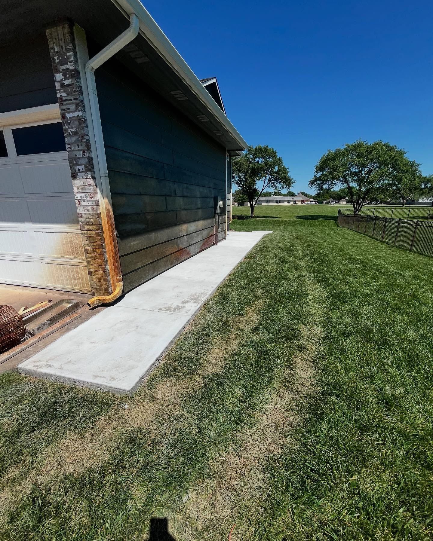 A before and after picture of a house with a concrete walkway leading to it.