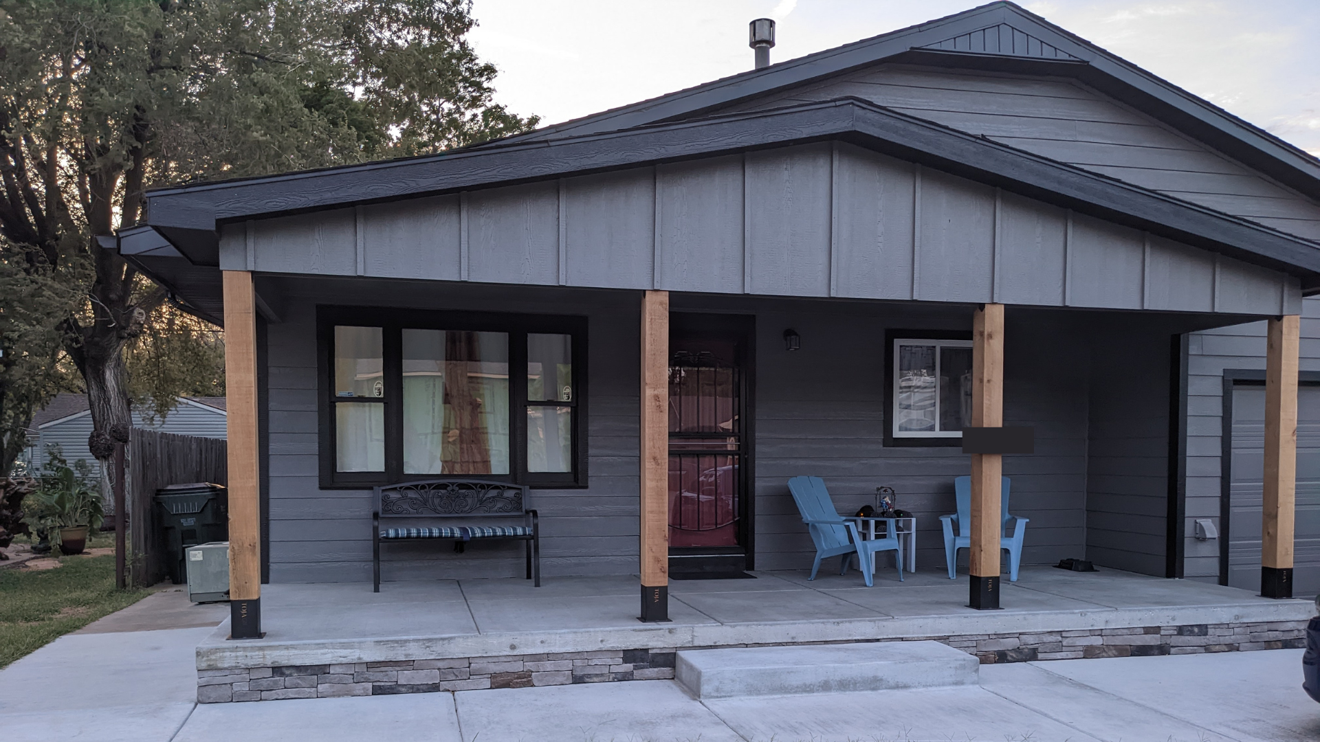 A gray house with a porch and chairs on it.