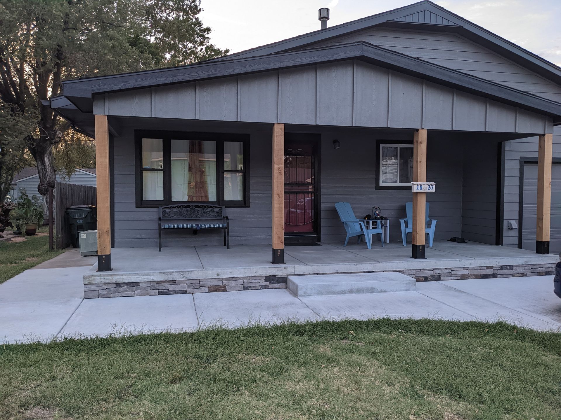 A gray house with a porch and a table and chairs on it.