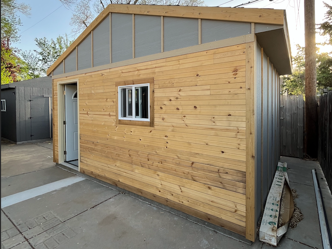 A small wooden shed with a window in the backyard.