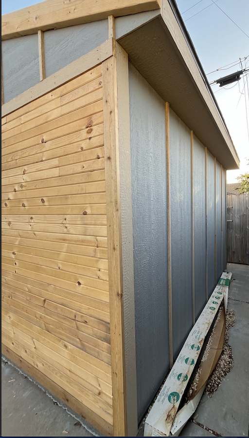A shed with wooden siding and a metal roof