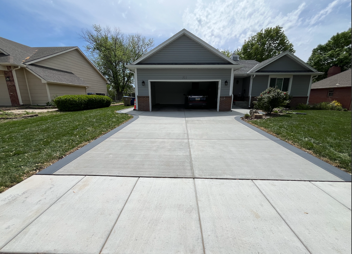 A driveway leading to a house with a car parked in the garage.