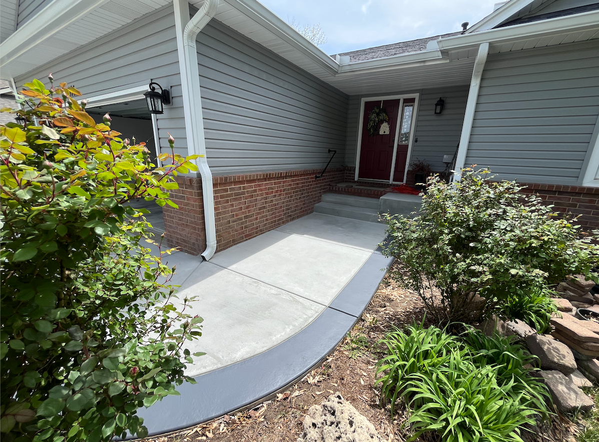 A concrete walkway leading to the front door of a house.