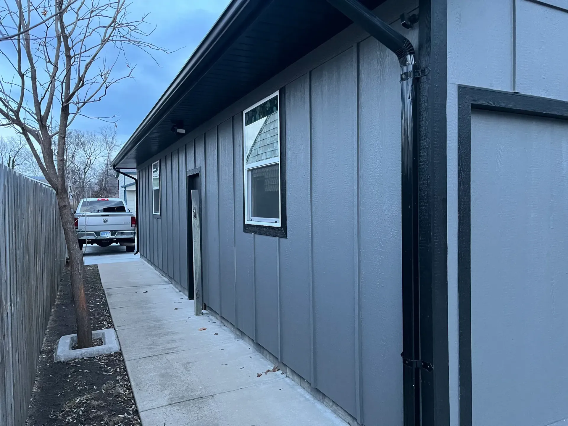 A gray house with a white truck parked in front of it.