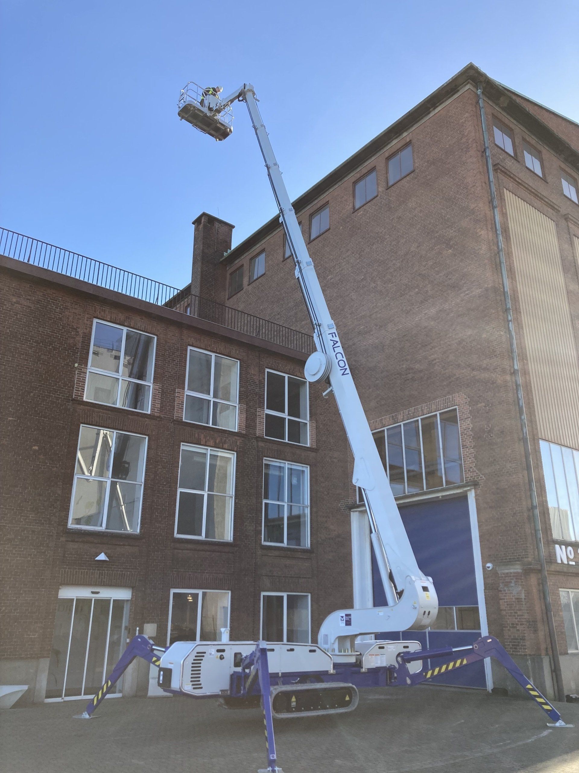 A crane is sitting in front of a large brick building