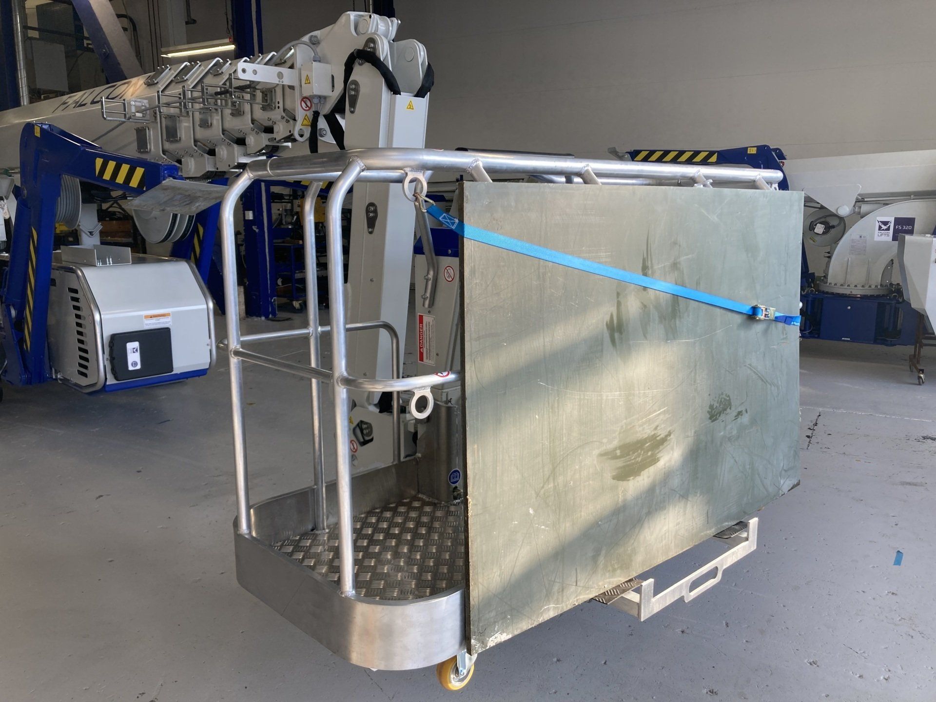 A metal cart with a blue strap attached to it is sitting in a garage.