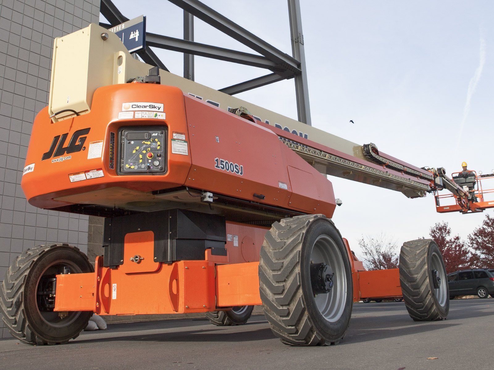An orange jlg lift is parked in front of a building