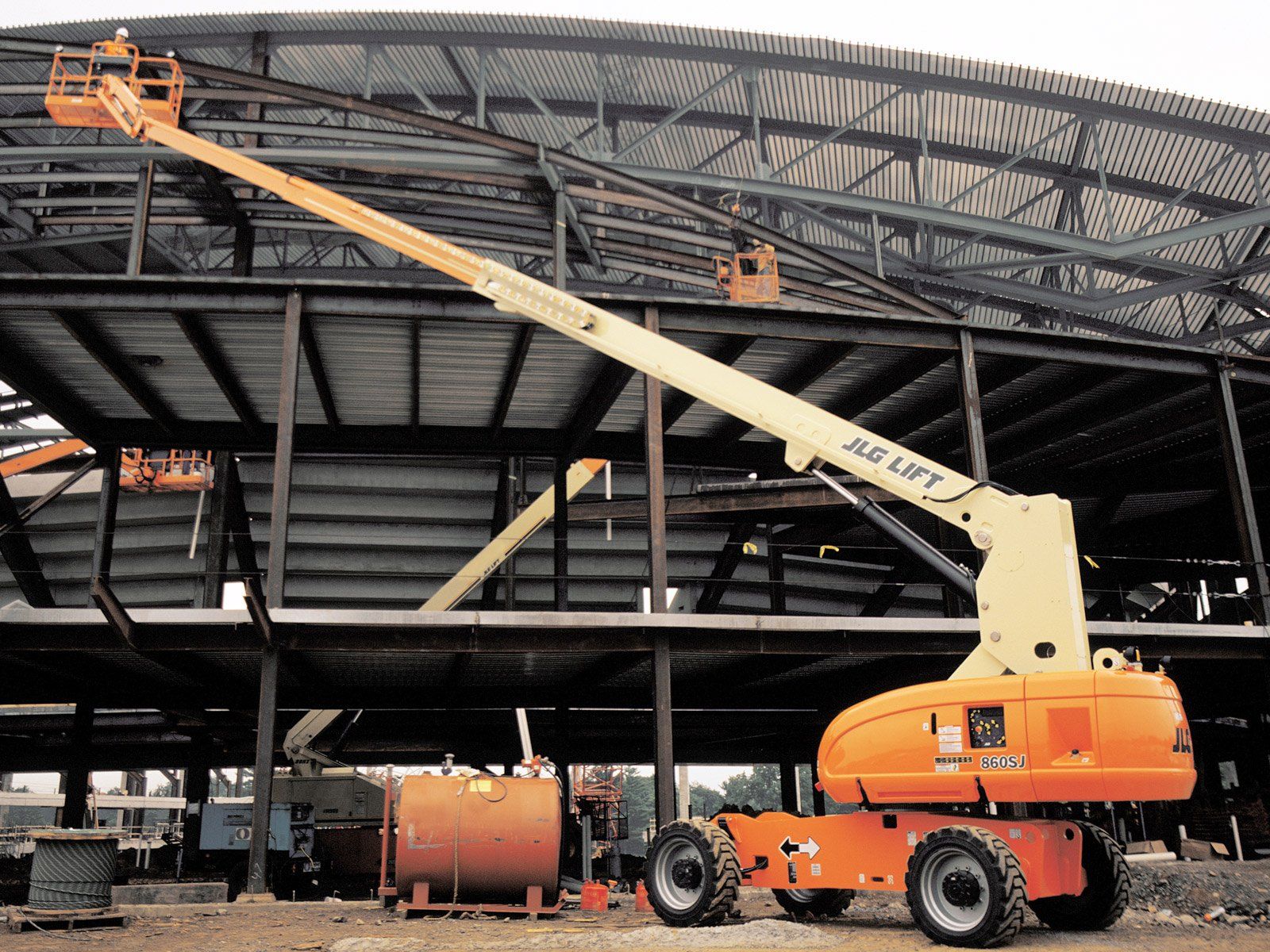 An orange jlg lift is parked in front of a building under construction