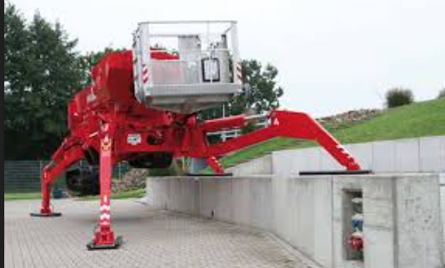 A red crane is sitting on top of a concrete wall.