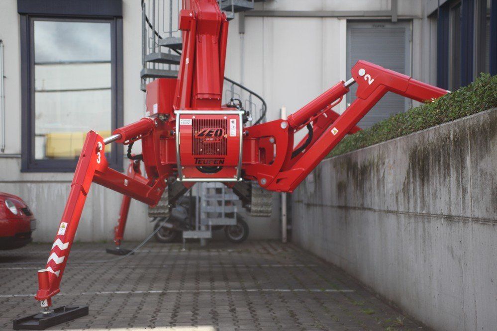 A red spider crane is parked in front of a building