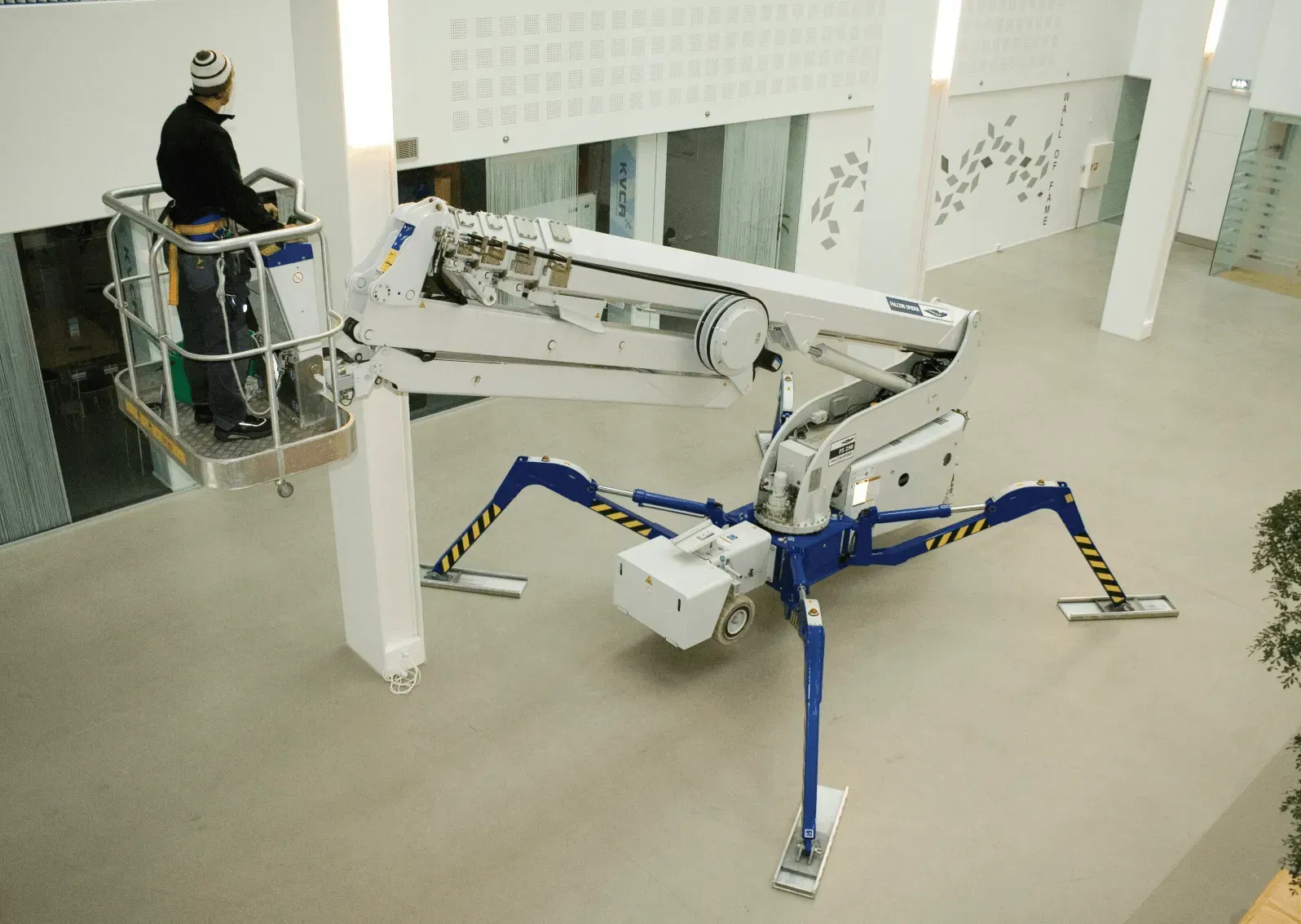 A man is working on a spider lift in a building.