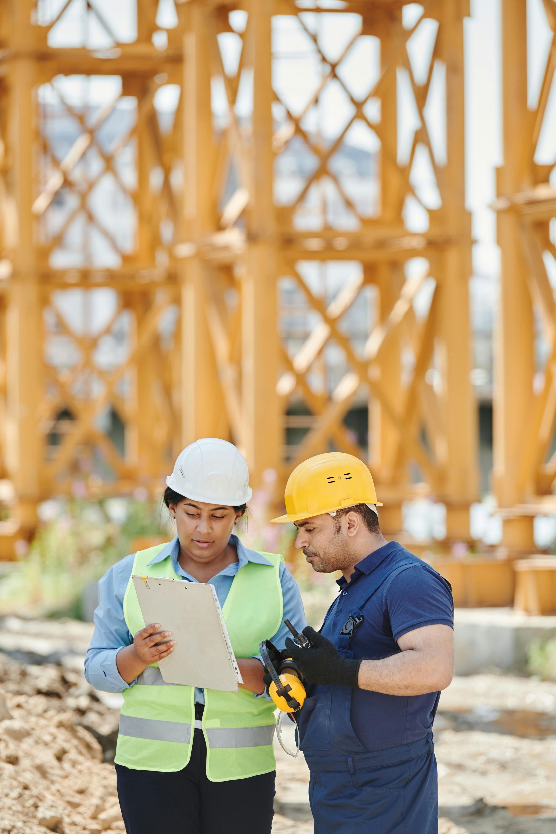 Two people in safety helmets conducting a rental inspection at a construction site, ensuring equipment safety and compliance