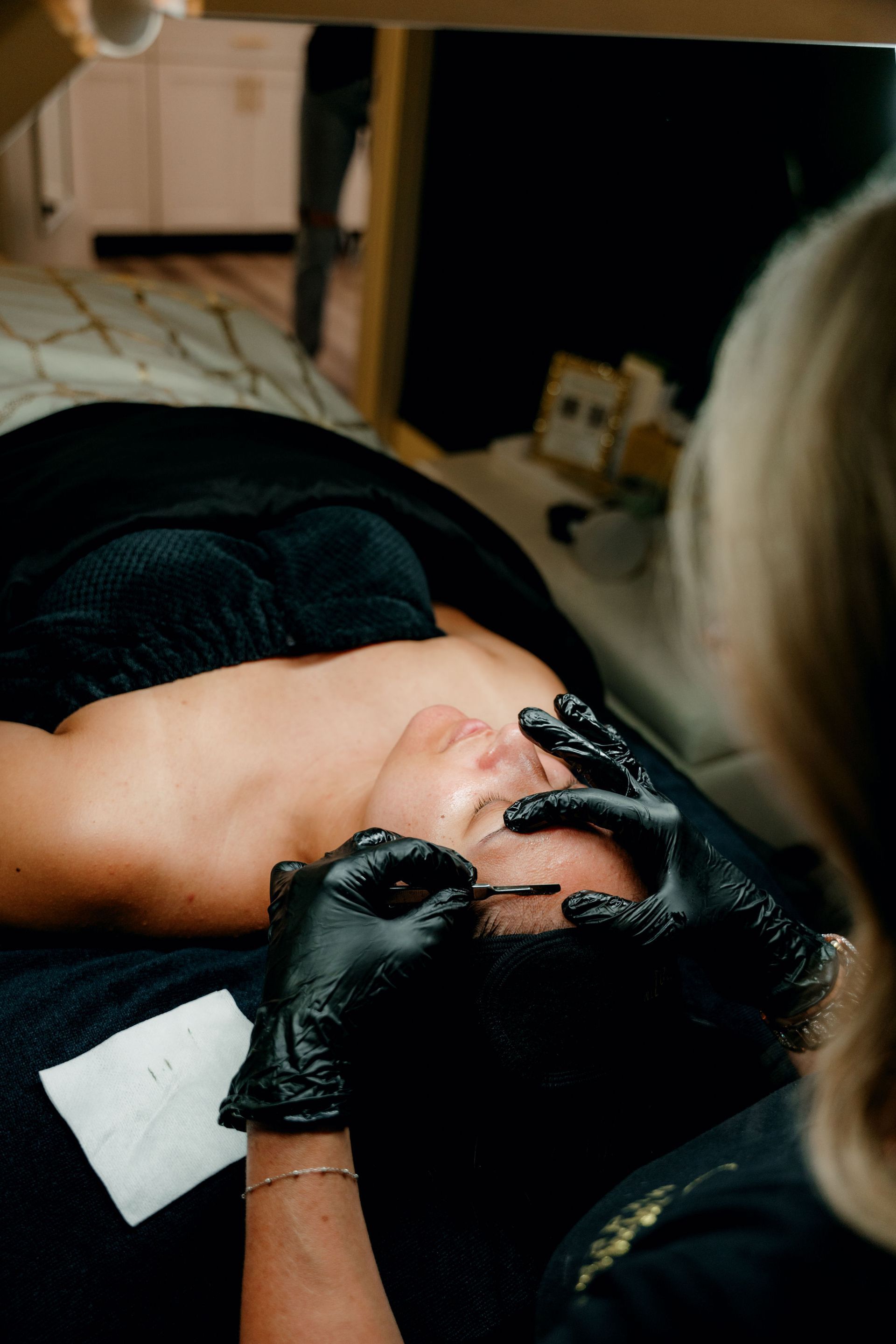 A woman is laying on a bed getting a facial treatment.