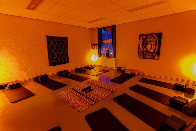 Een kamer vol yogamatten en een schilderij aan de muur.