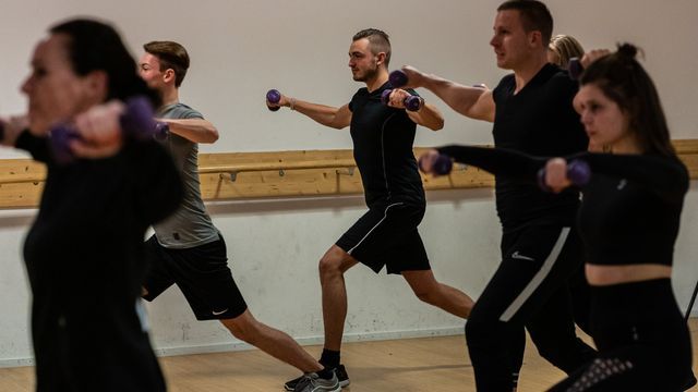 Een groep mensen doet oefeningen met halters in een sportschool.