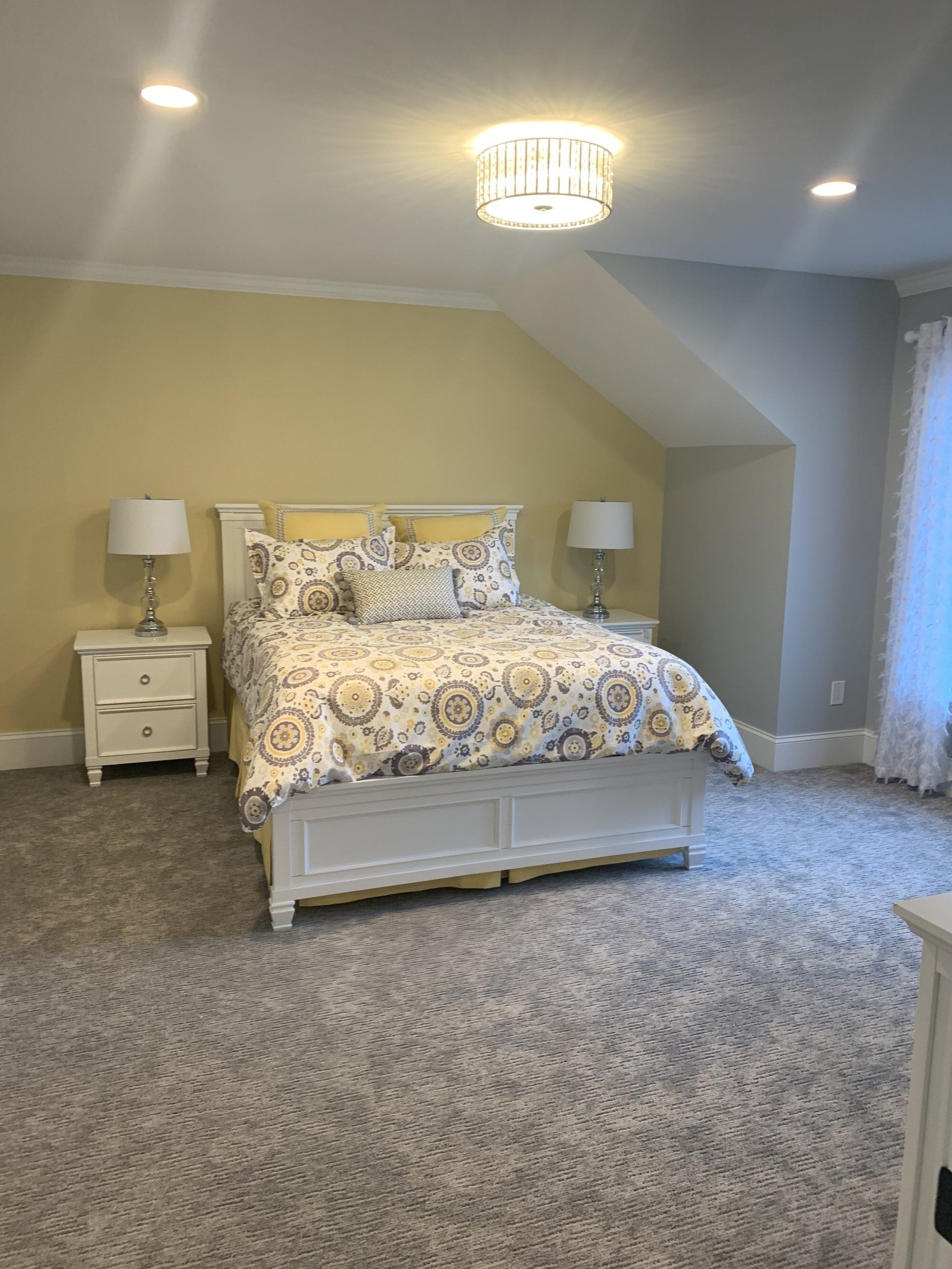 A bedroom with a bed , nightstands , lamps and a window.