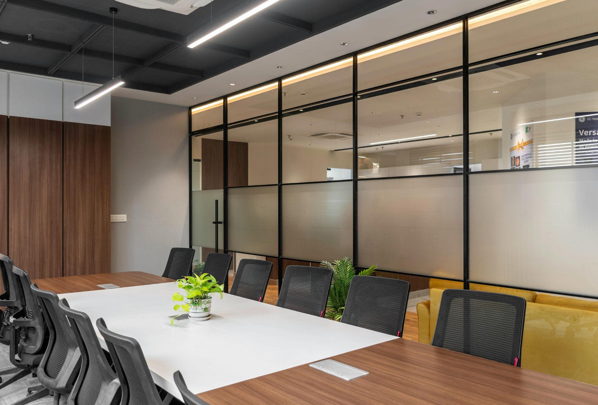 Conference room with a large wooden table, black chairs, and a glass wall.