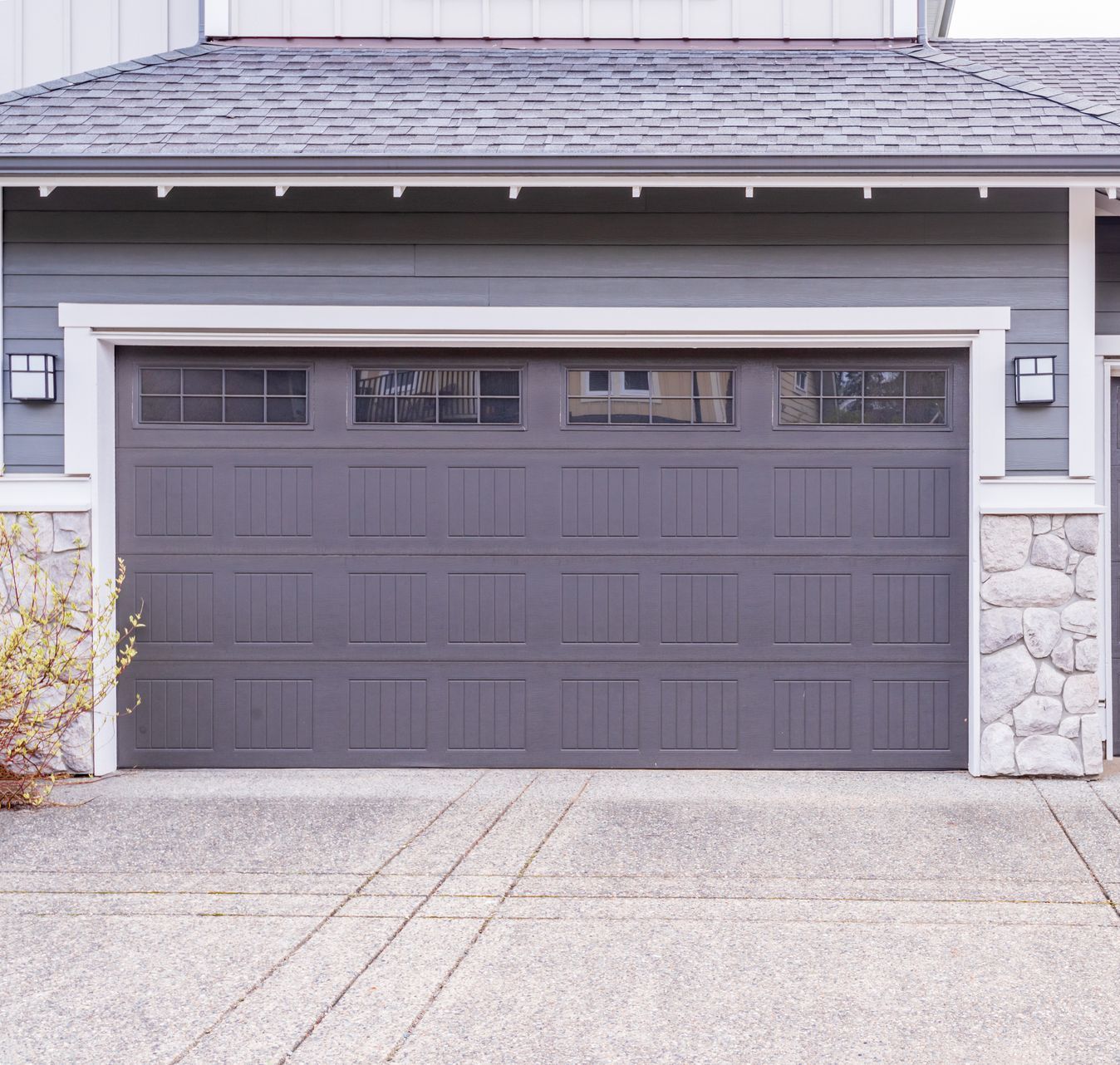 A large gray garage door is sitting in front of a house.