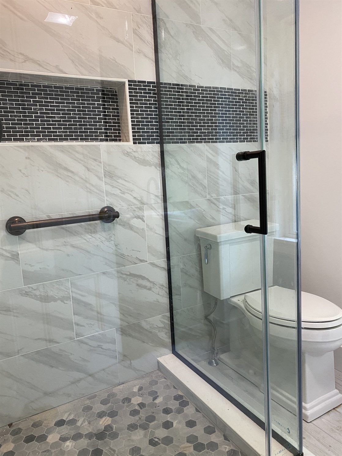 A bathroom with a toilet and a walk in shower with a glass door.