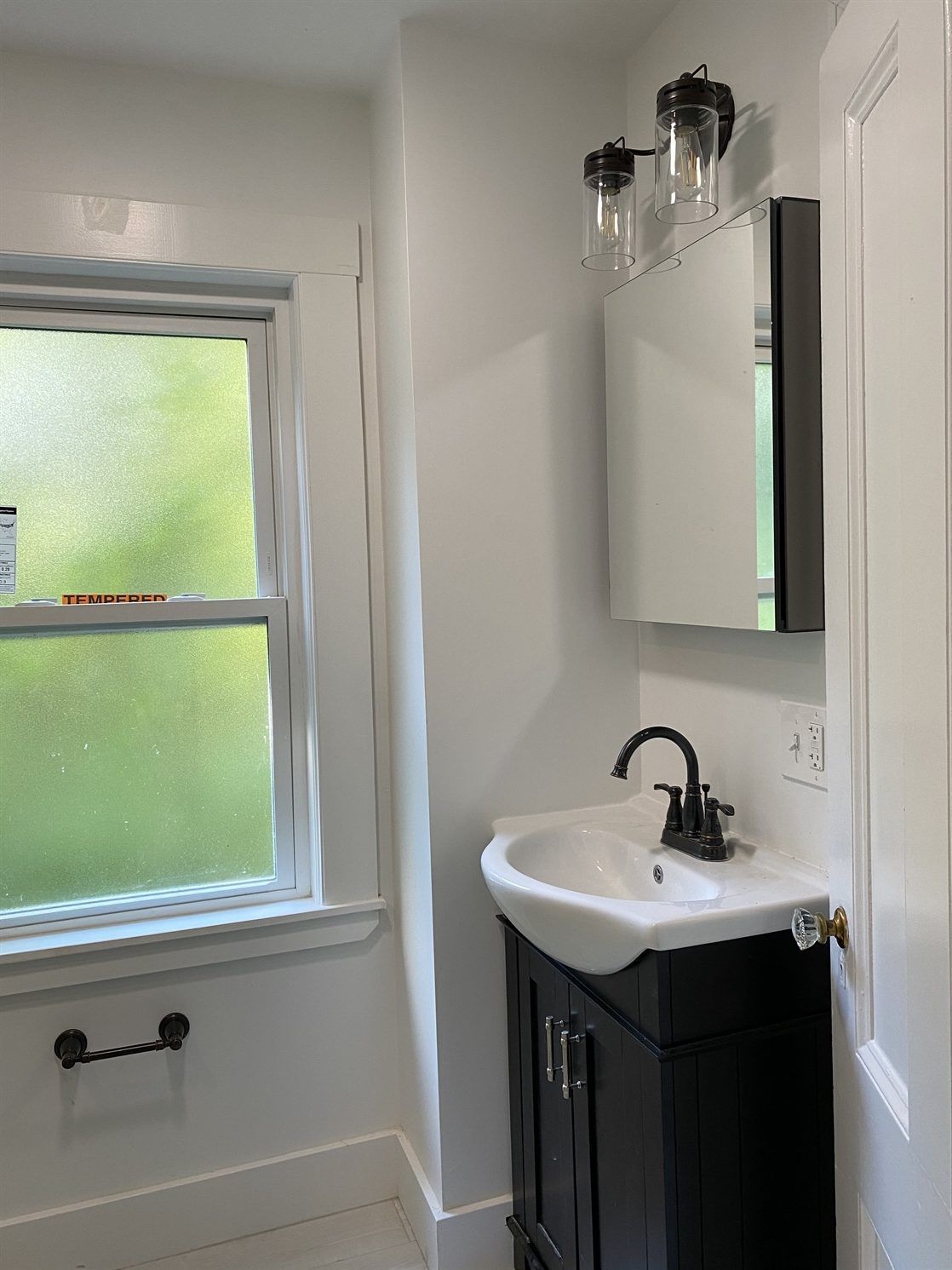 A bathroom with a sink , mirror and window.