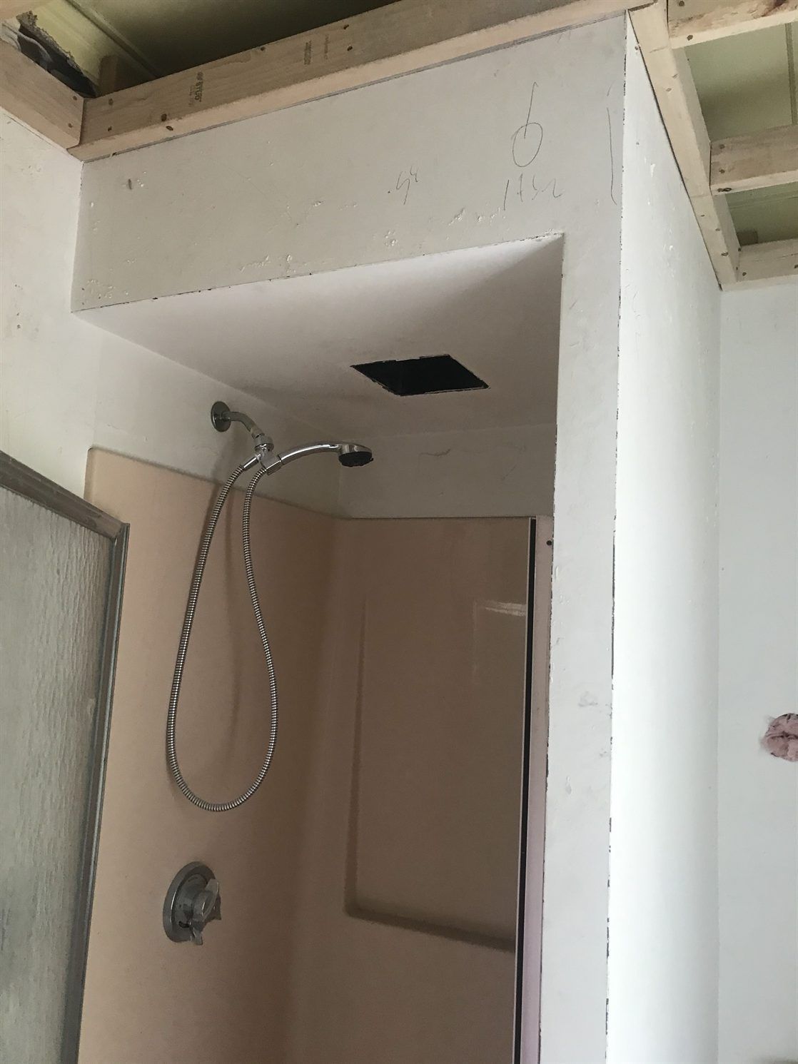 A shower head is hanging from the ceiling in a bathroom under construction.