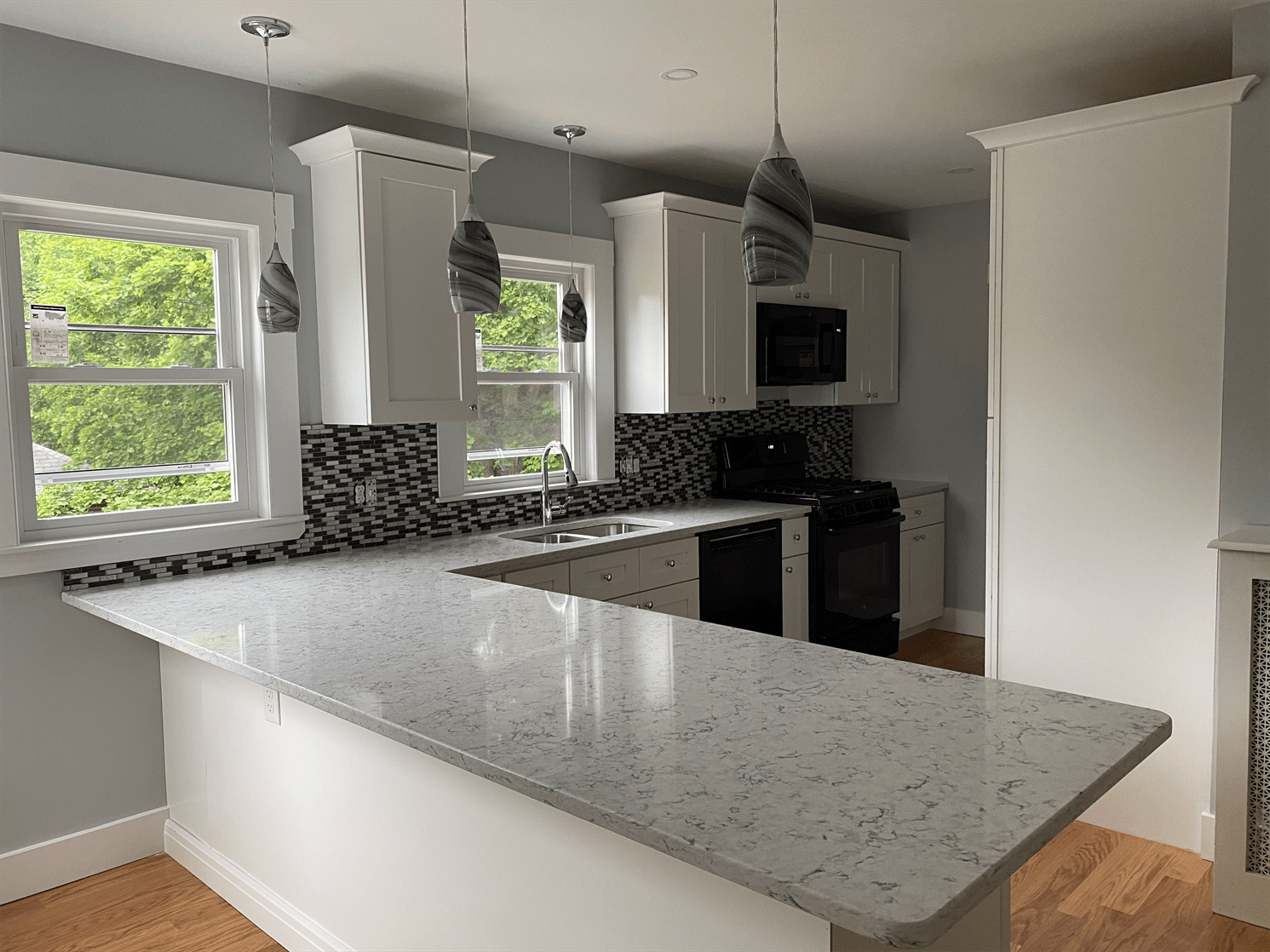 A kitchen with white cabinets , granite counter tops , a stove and a sink.
