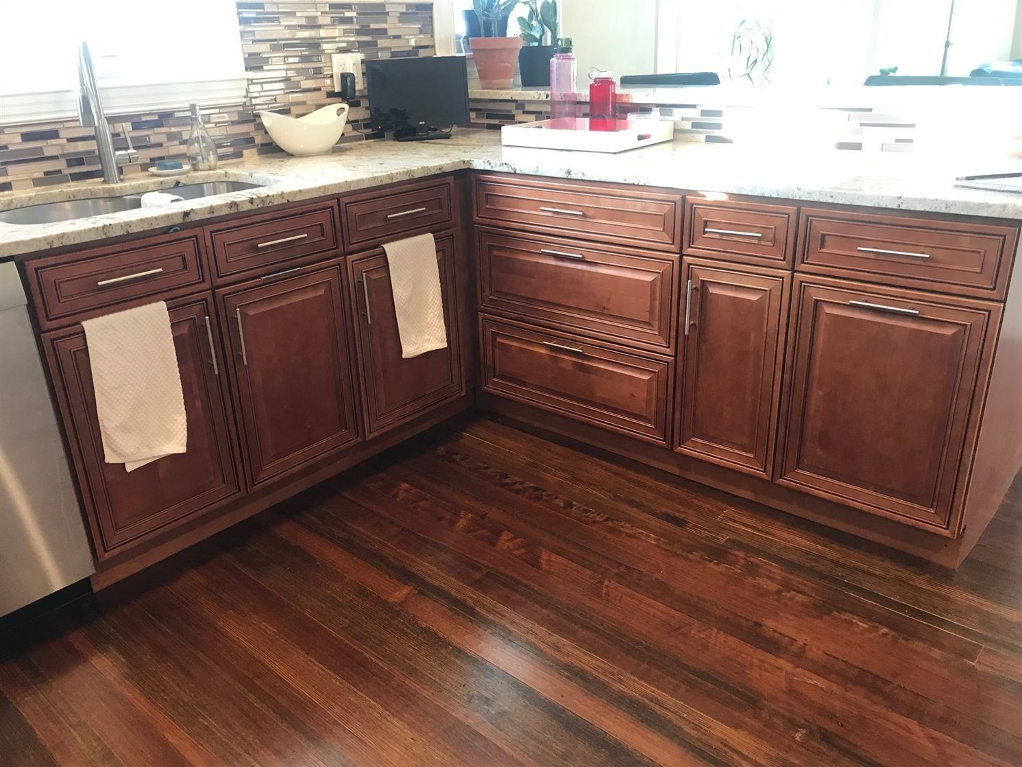 A kitchen with wooden cabinets , stainless steel appliances , and hardwood floors.
