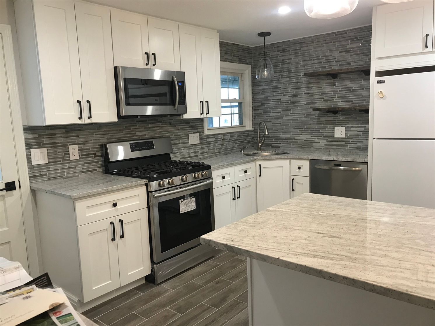 A kitchen with white cabinets , stainless steel appliances , granite counter tops and a large island.