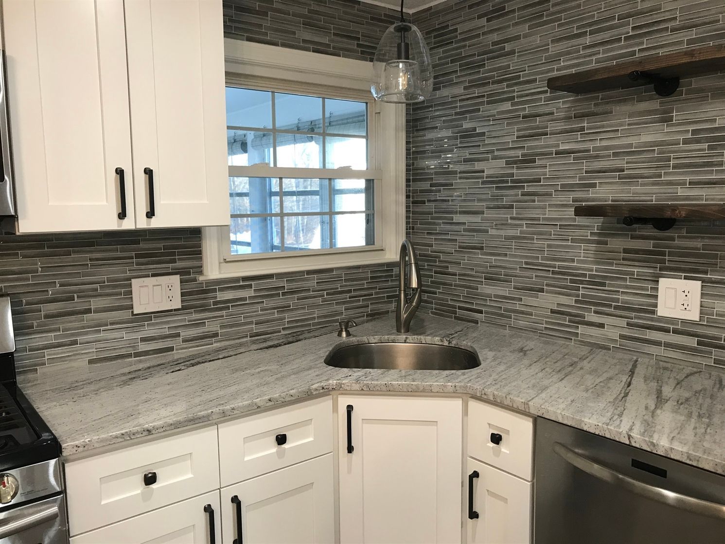 A kitchen with white cabinets , stainless steel appliances , a sink and a window.