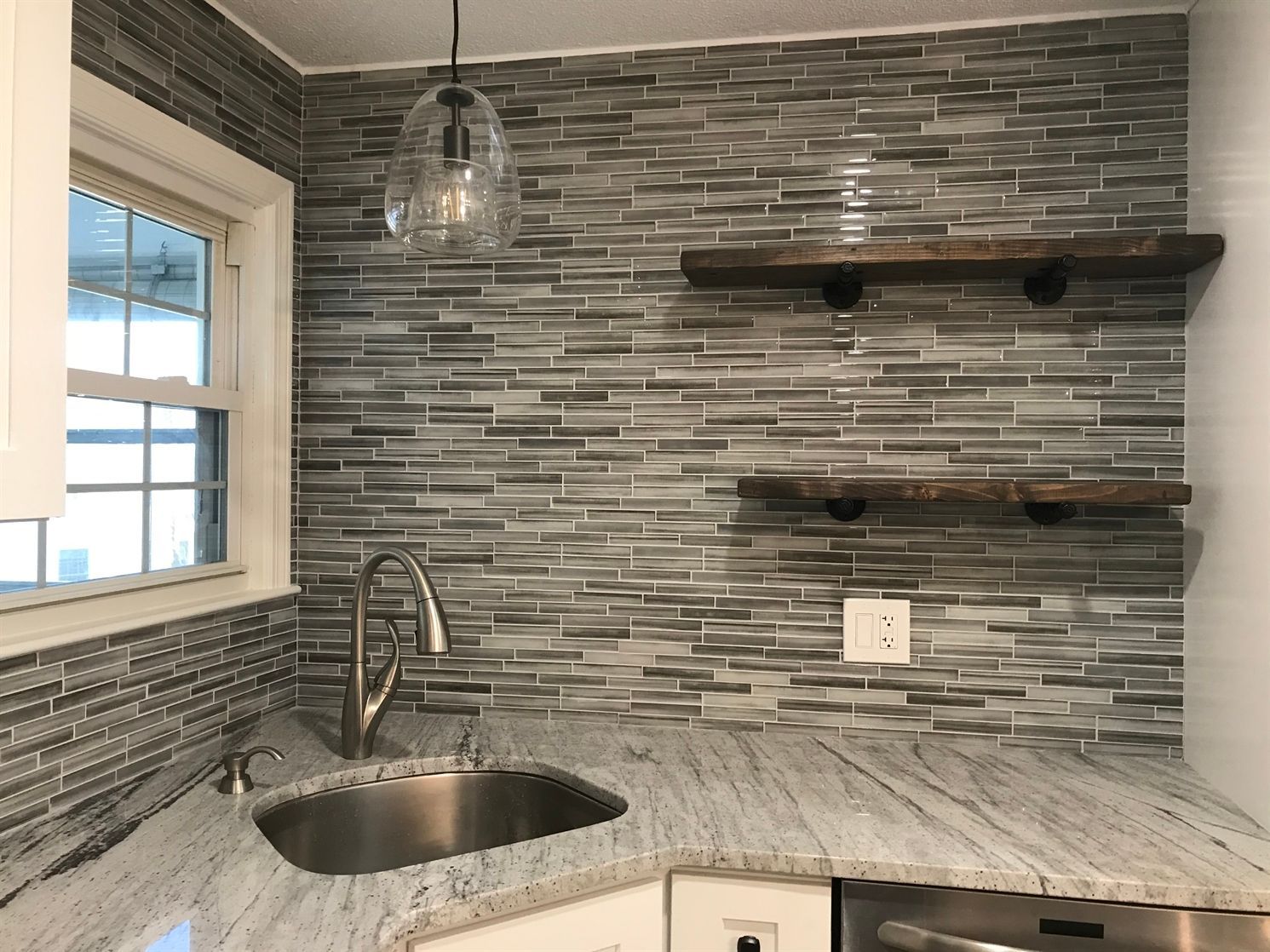 A kitchen with a sink , dishwasher , and shelves.