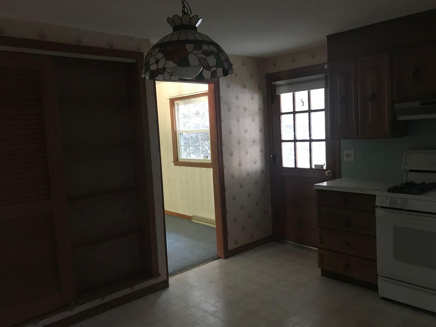 An empty kitchen with a stove and a lamp hanging from the ceiling