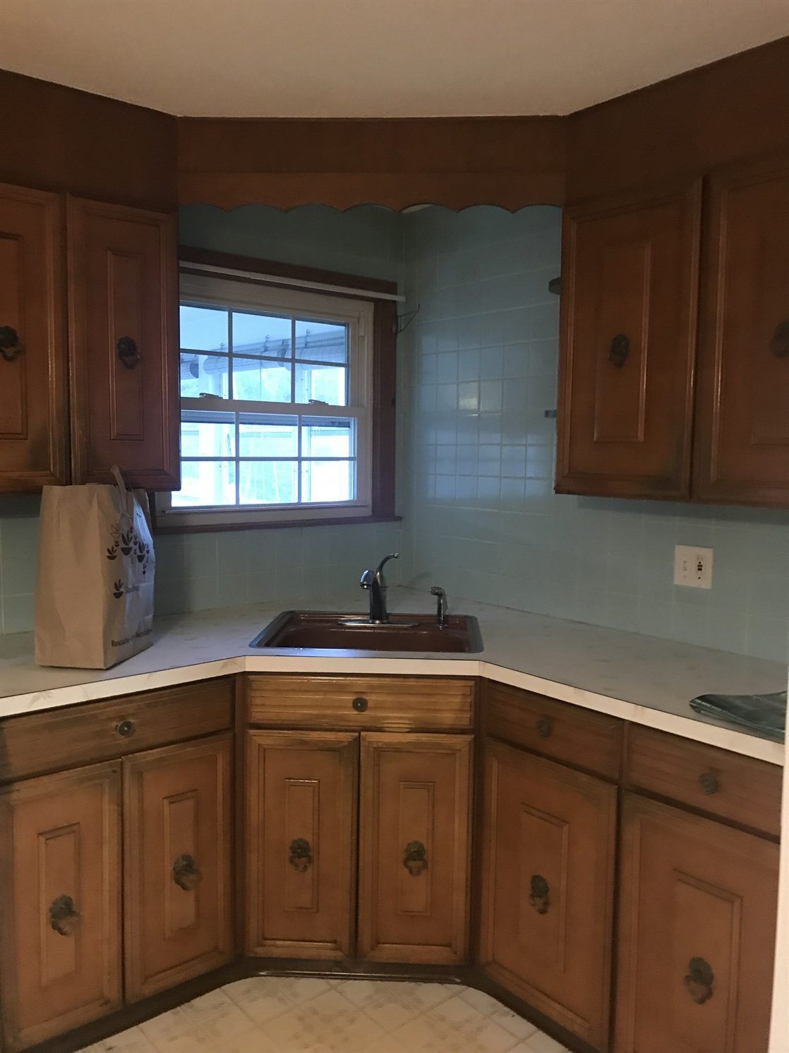 A kitchen with wooden cabinets , a sink , and a window.