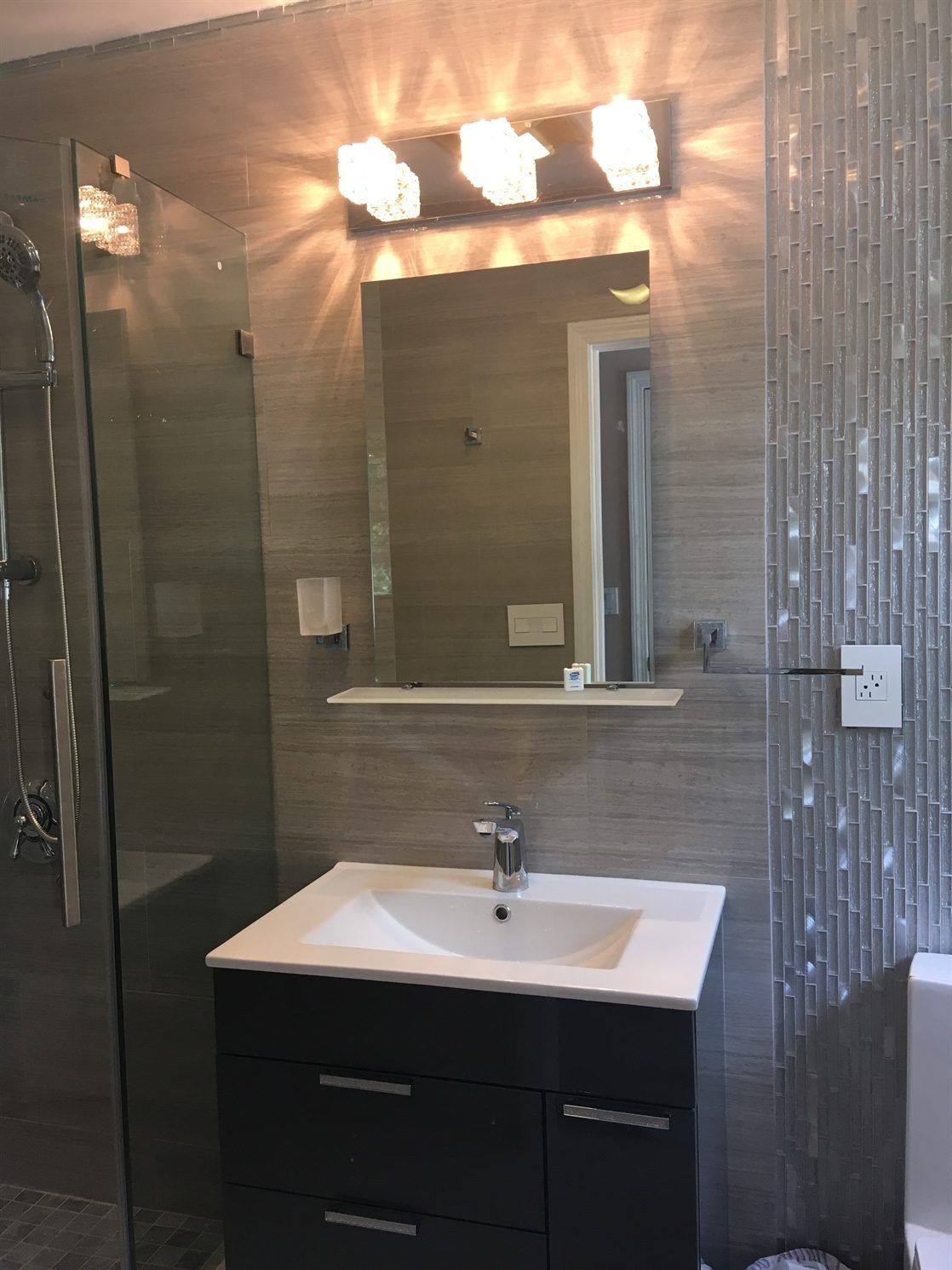 A bathroom with a sink , mirror and walk in shower.