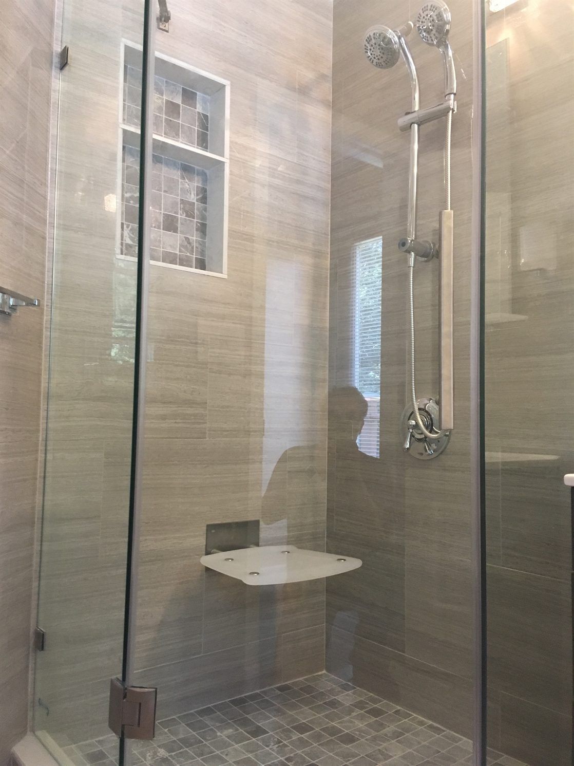A walk in shower with a glass door and a seat.