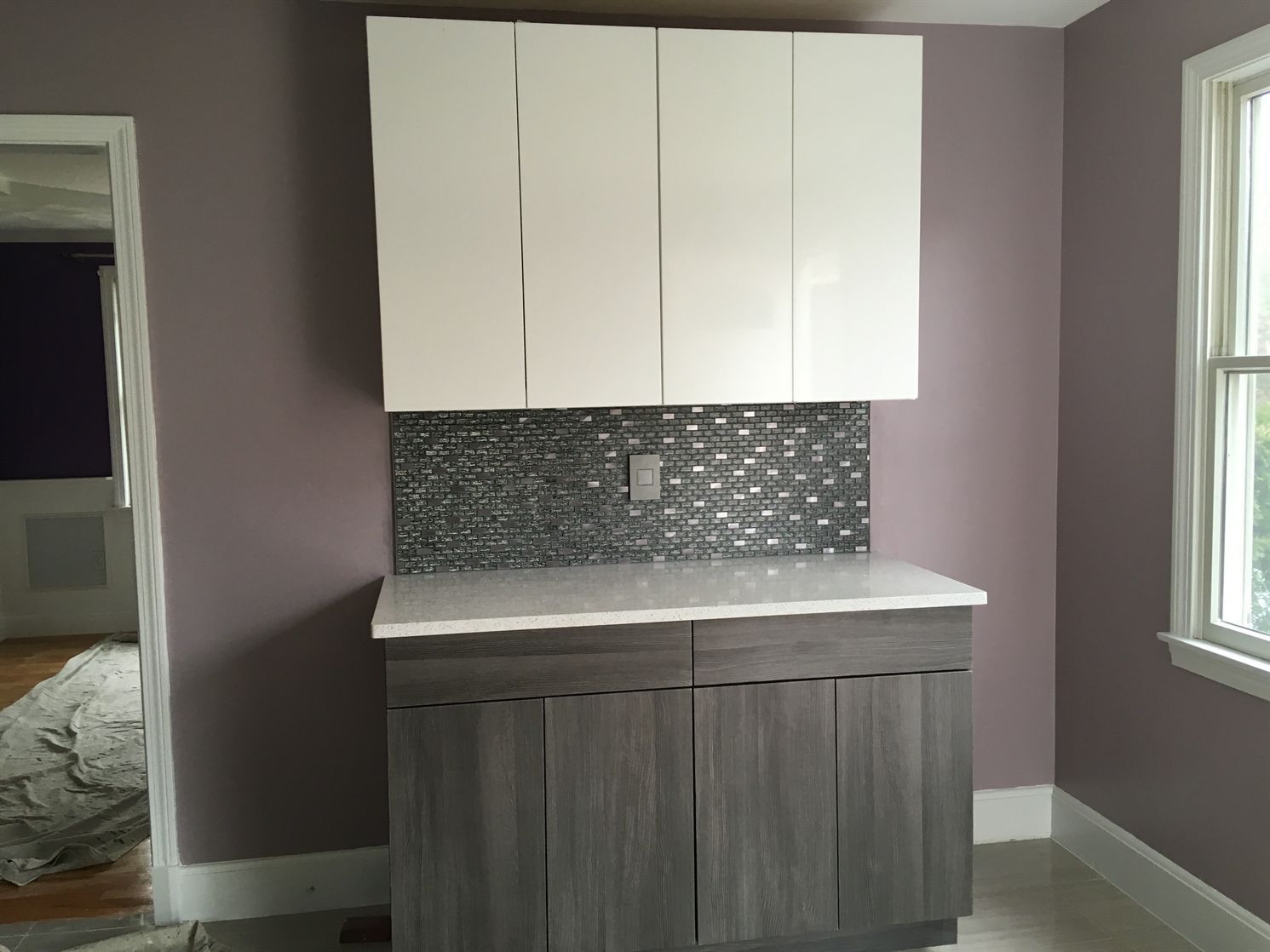 A kitchen with purple walls and white cabinets