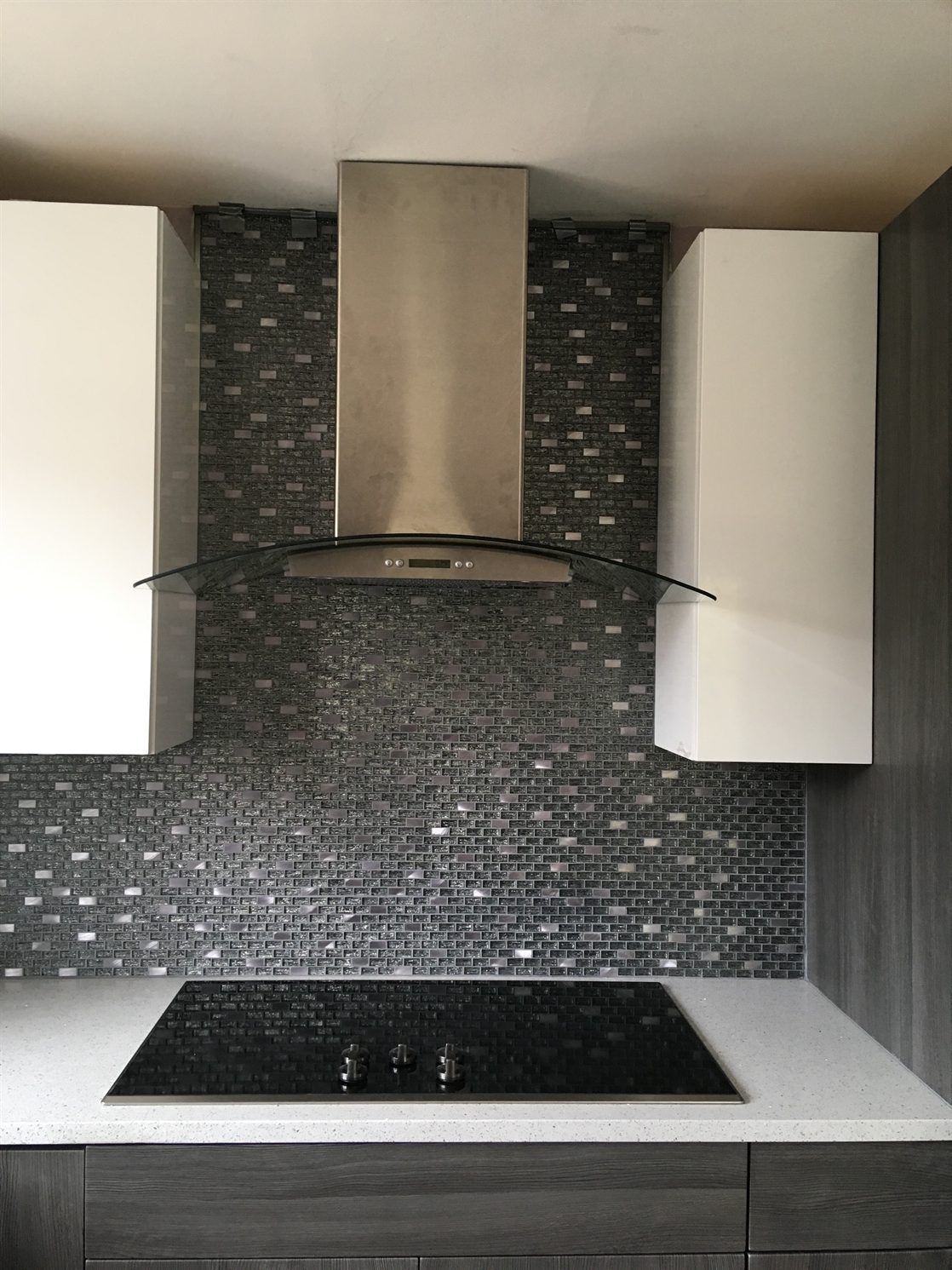A kitchen with a stove top oven and a hood above it.
