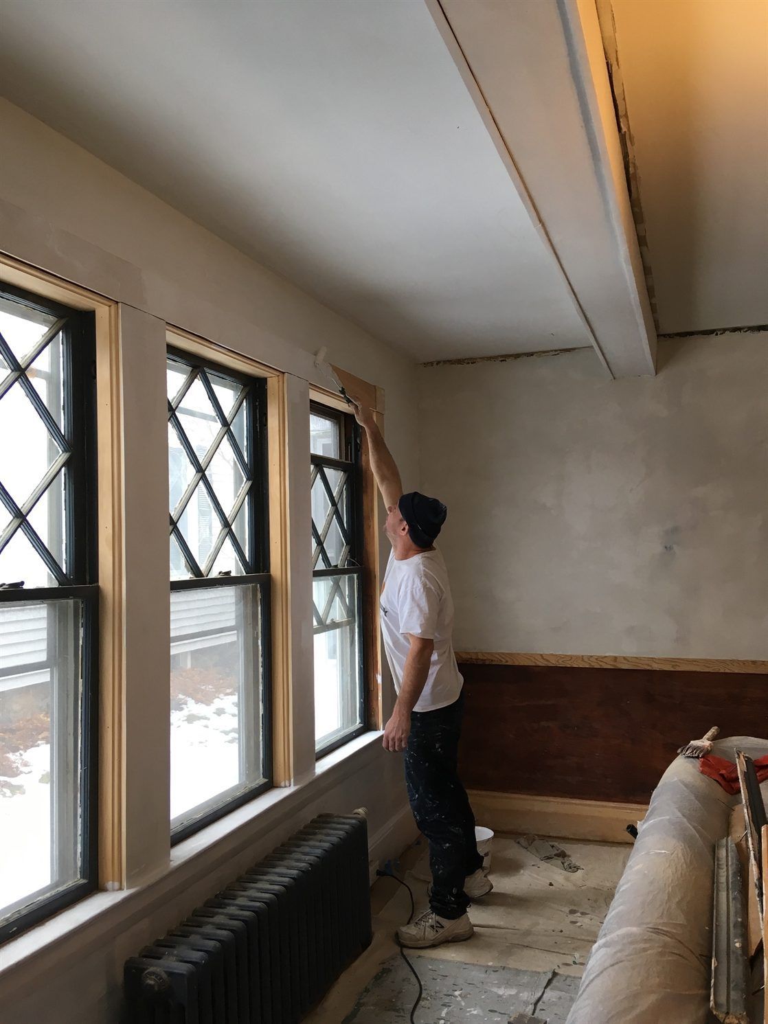 A man is painting a window in a room.