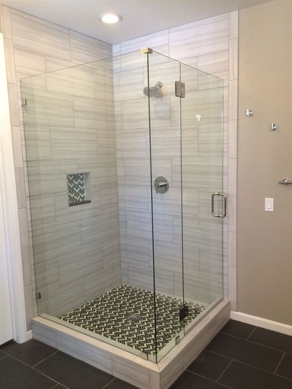 A bathroom with a walk in shower with a glass door.
