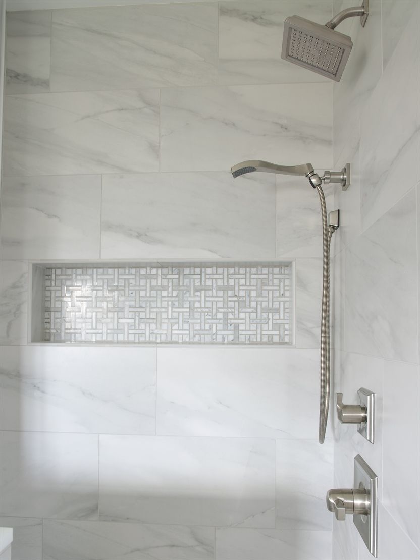 A bathroom with white tiles and a shower head.