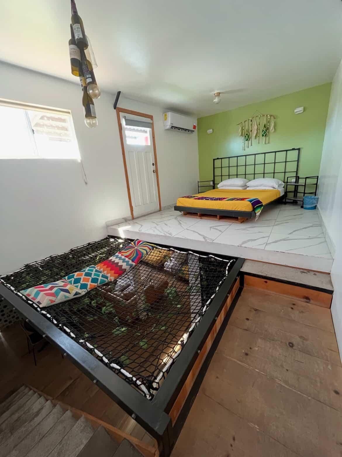 Bedroom with a bed on a raised platform, hammock-style net, and green walls.