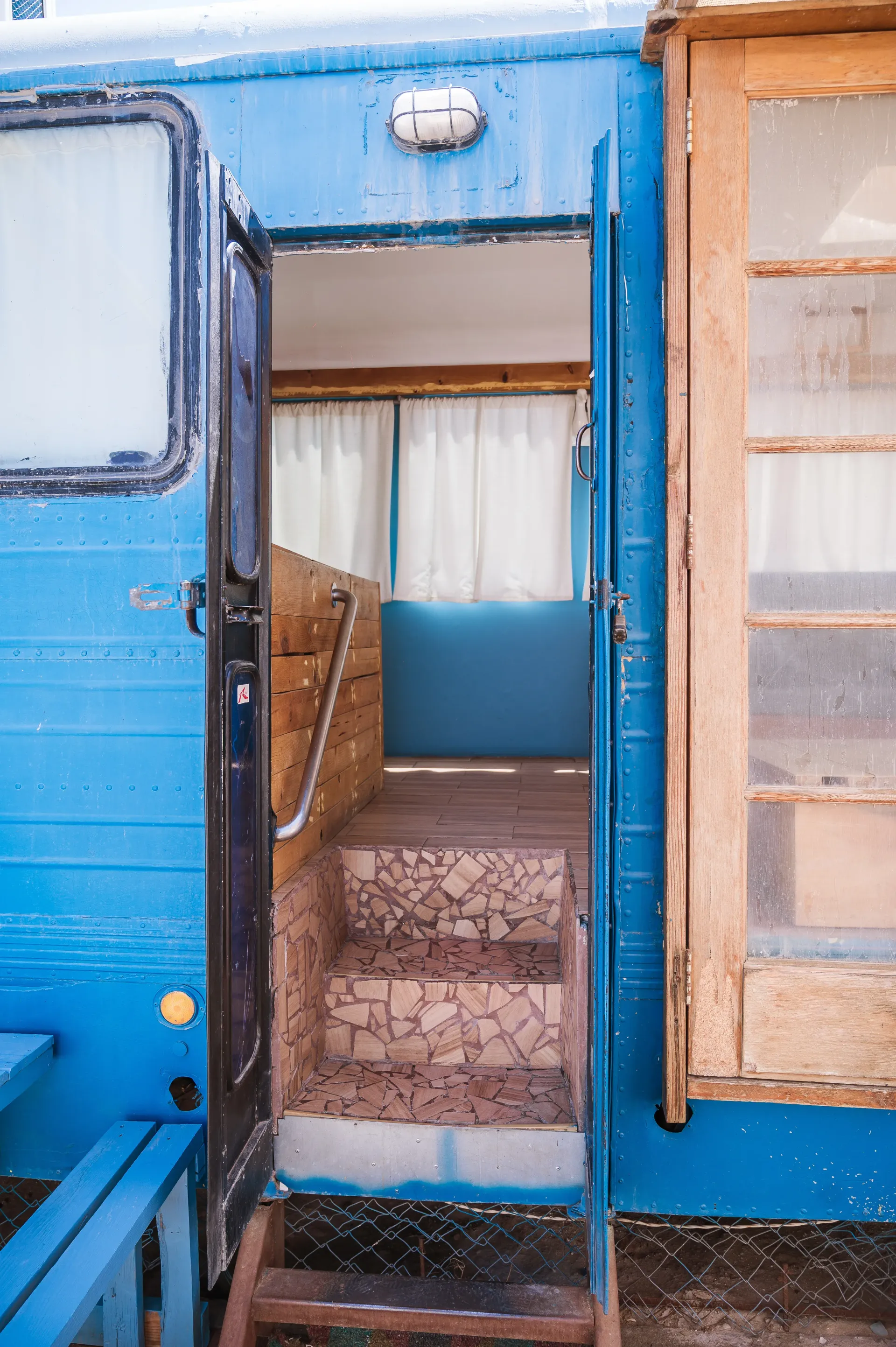 Blue camper door open to interior with wooden stairs.