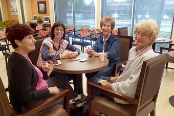 A Group of Senior Women Sitting Around a Table Playing Uno — Tustin, CA — Americana Senior Care