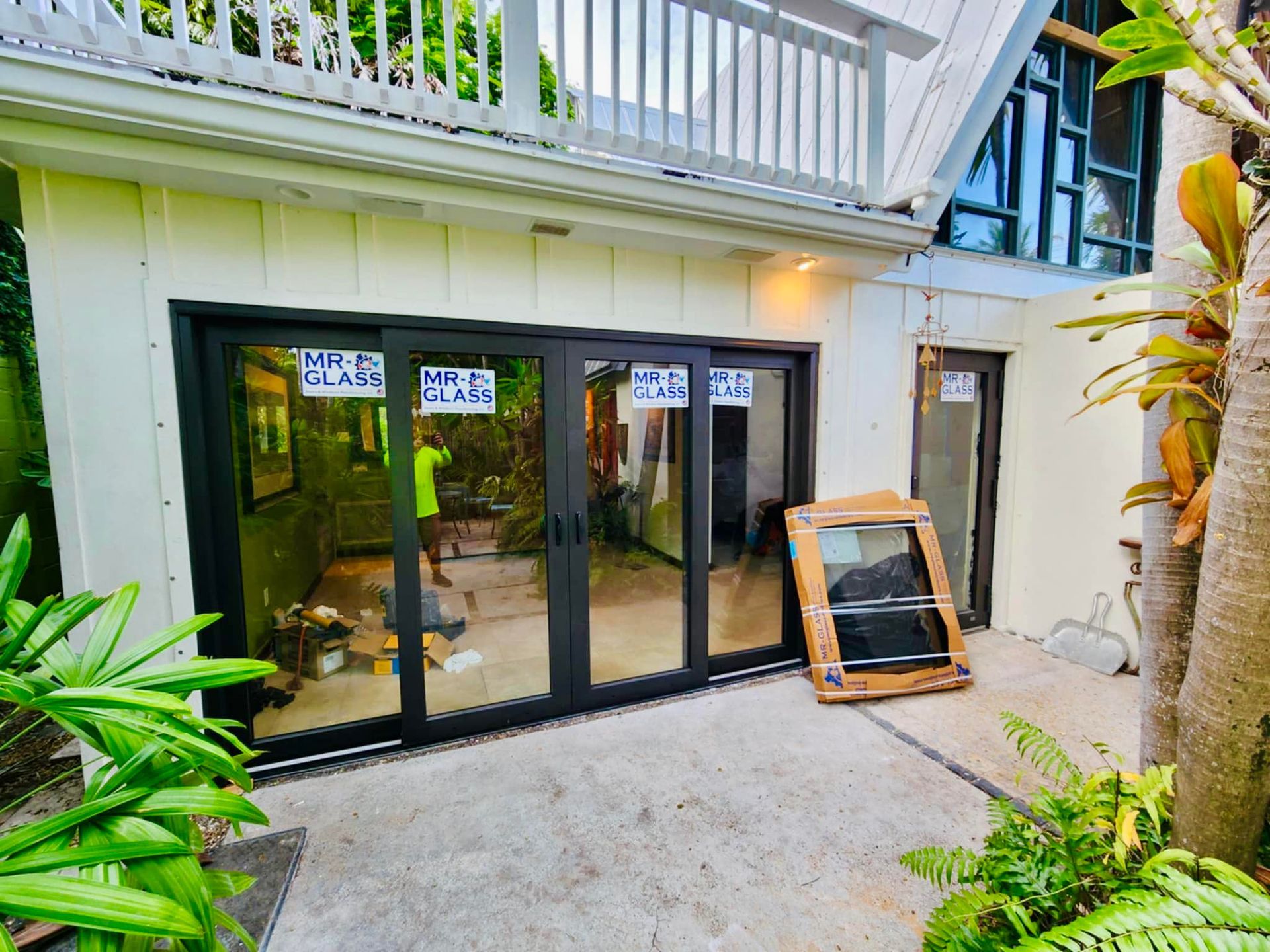 A man is standing in front of a house with sliding glass doors.