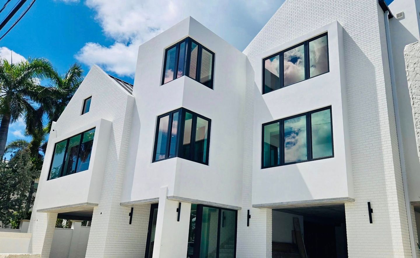 A white building with a lot of windows and a palm tree in the background.