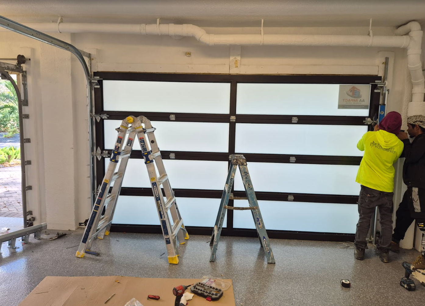 A white house with a brick wall and a large glass door.