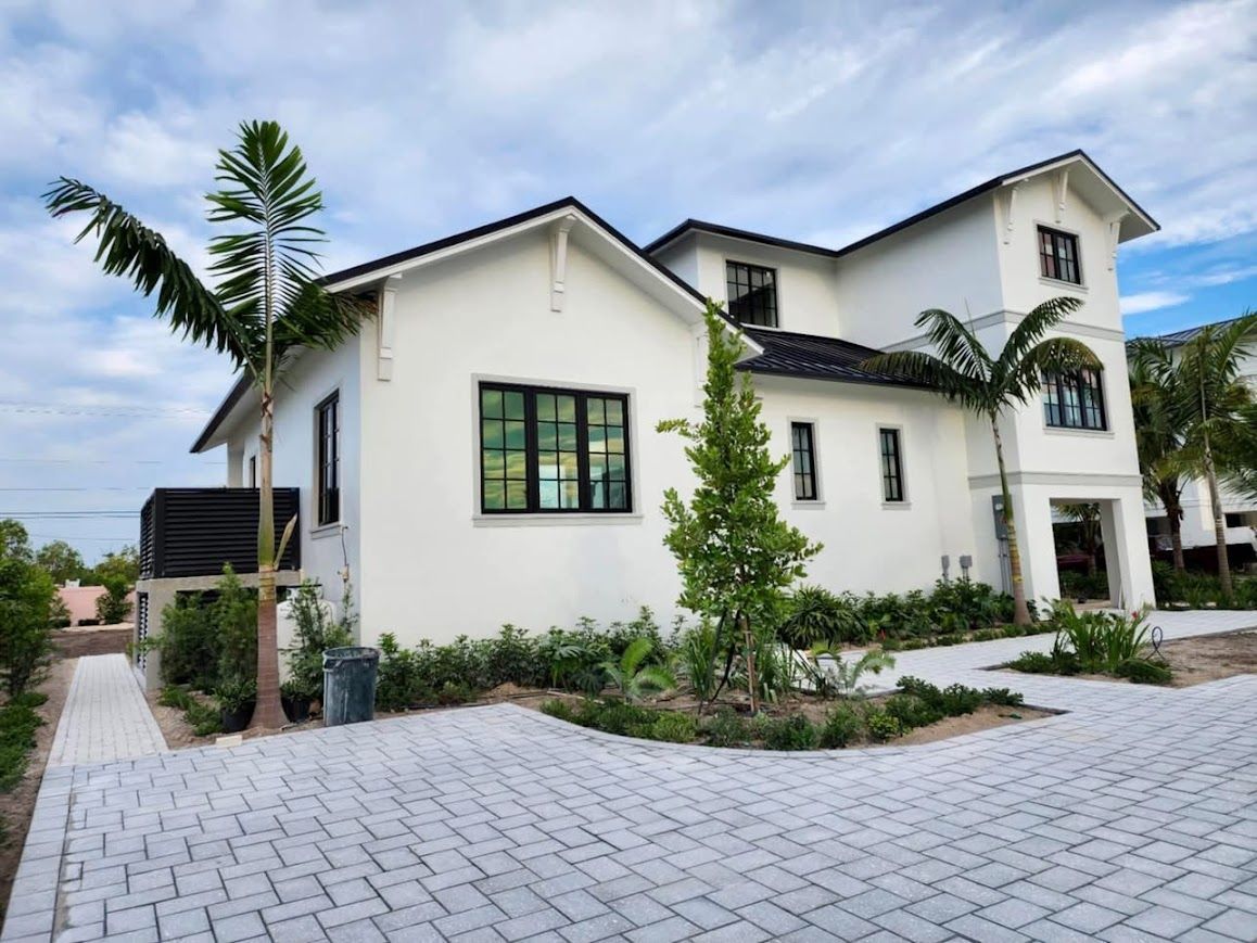 A large white house with a brick driveway in front of it