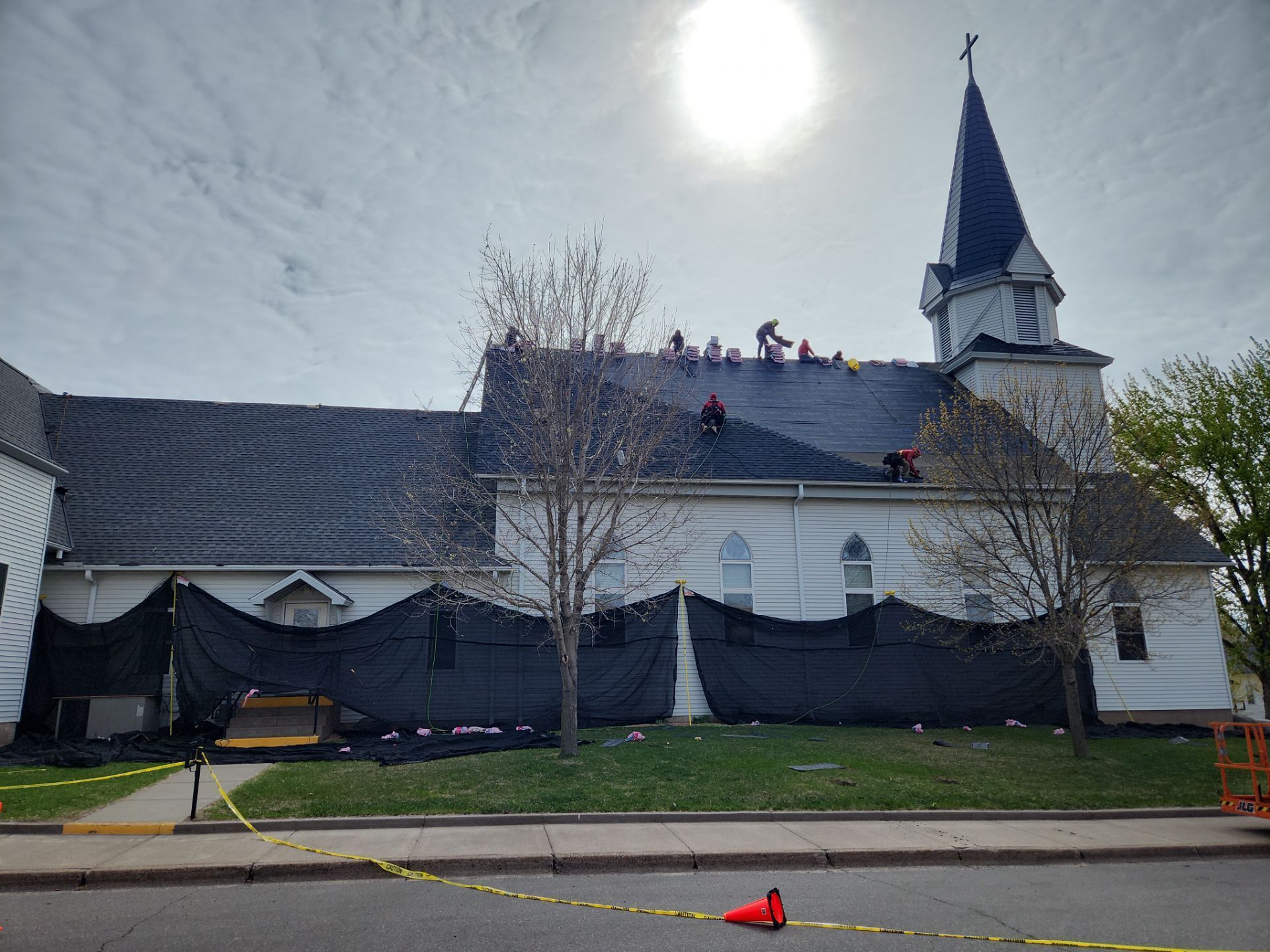 A new white bay window installed on a red wooden house exterior, with a ladder and caulk gun nearby.